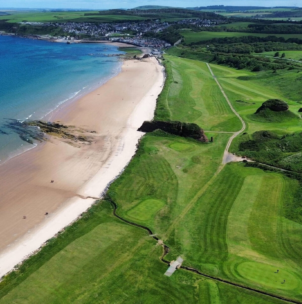 Sandy beach beside a coastal golf course